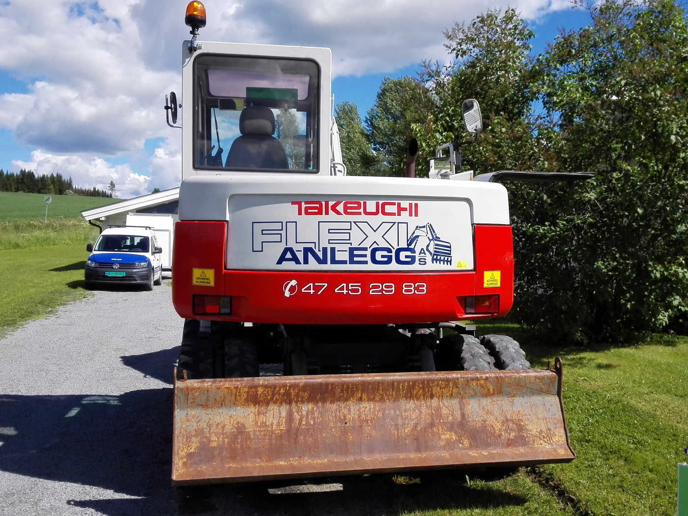 Middels står gravemaskin med logo og telfonnummer på gravemaskinloddet "Flexi anlegg"